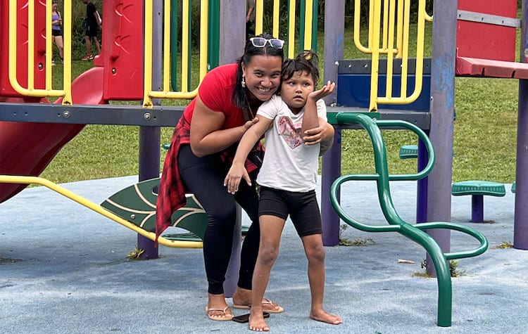 Photo: Mother and daughter stand in front of a playground